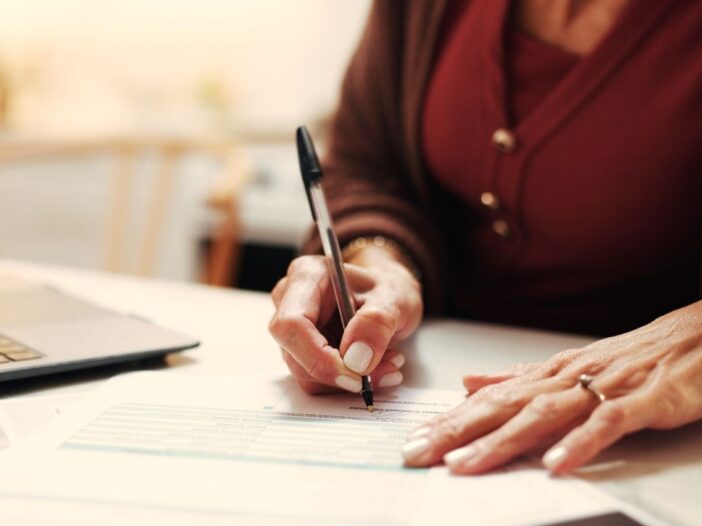 Agente immobiliare che sta firmando delle pratiche e sta registrado contratti online.