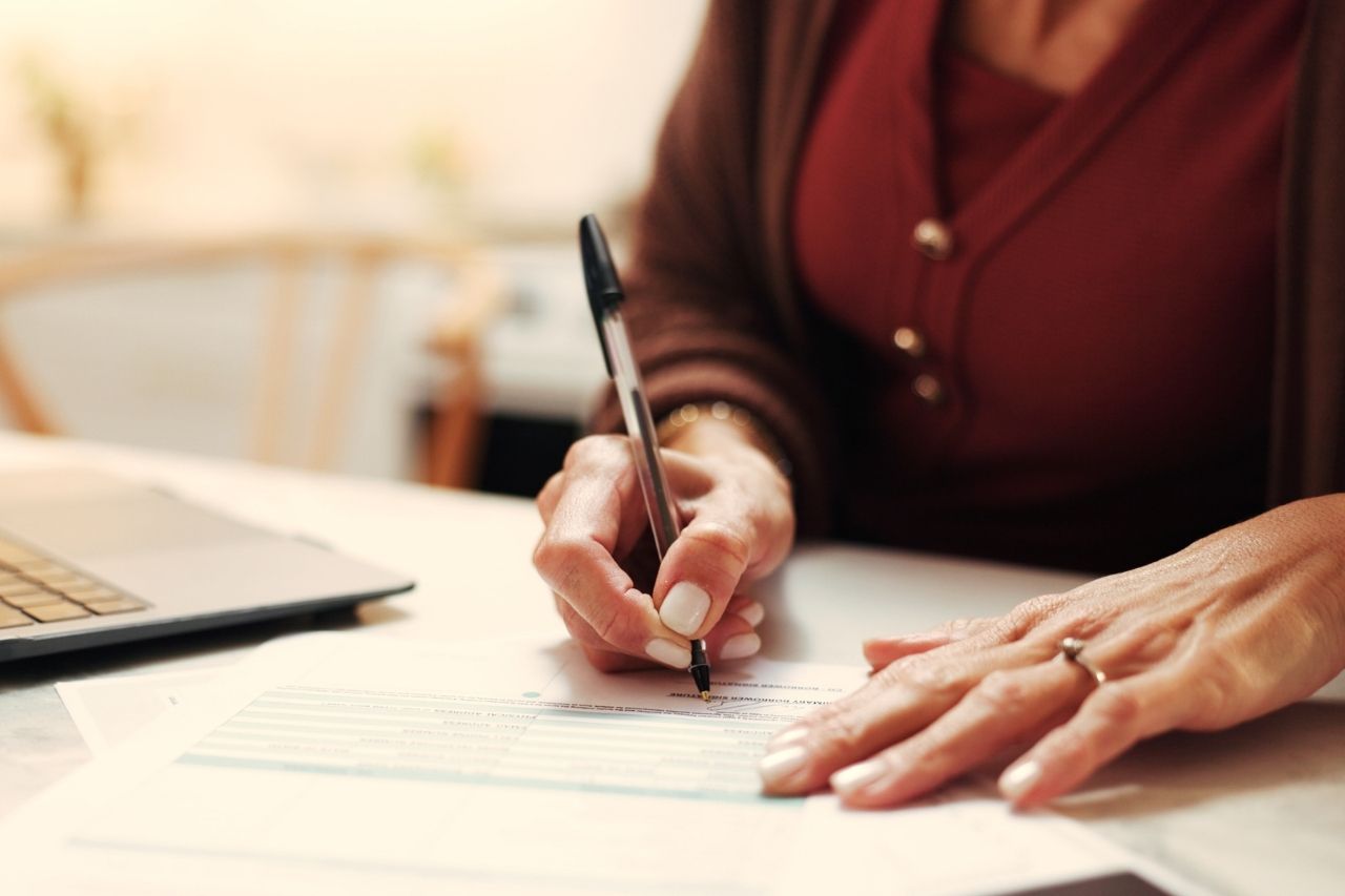 Agente immobiliare che sta firmando delle pratiche e sta registrado contratti online.